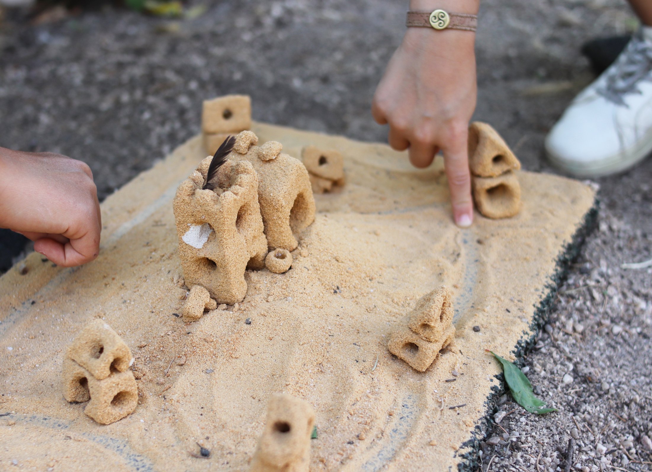 Preschool children collaboratively building sandcastles and structures in the playground.