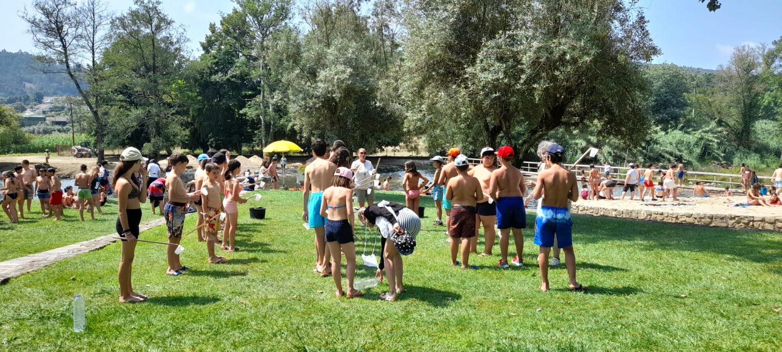 Preschool children participating in an outdoor nature activity by a river.