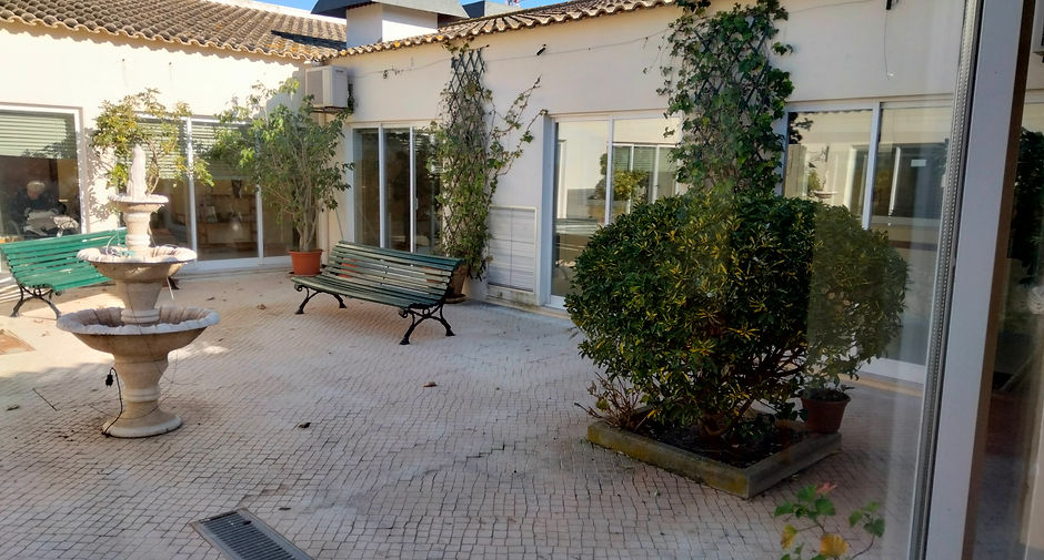 Peaceful courtyard at Centro Infantil "A Borboleta" preschool with benches and a fountain.