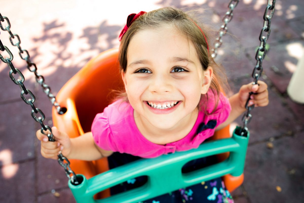 Happy preschool girl on a swing