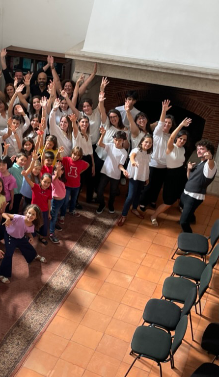 Children and adults singing together in a large group at Crescendo escolas de Músicas de Oeiras