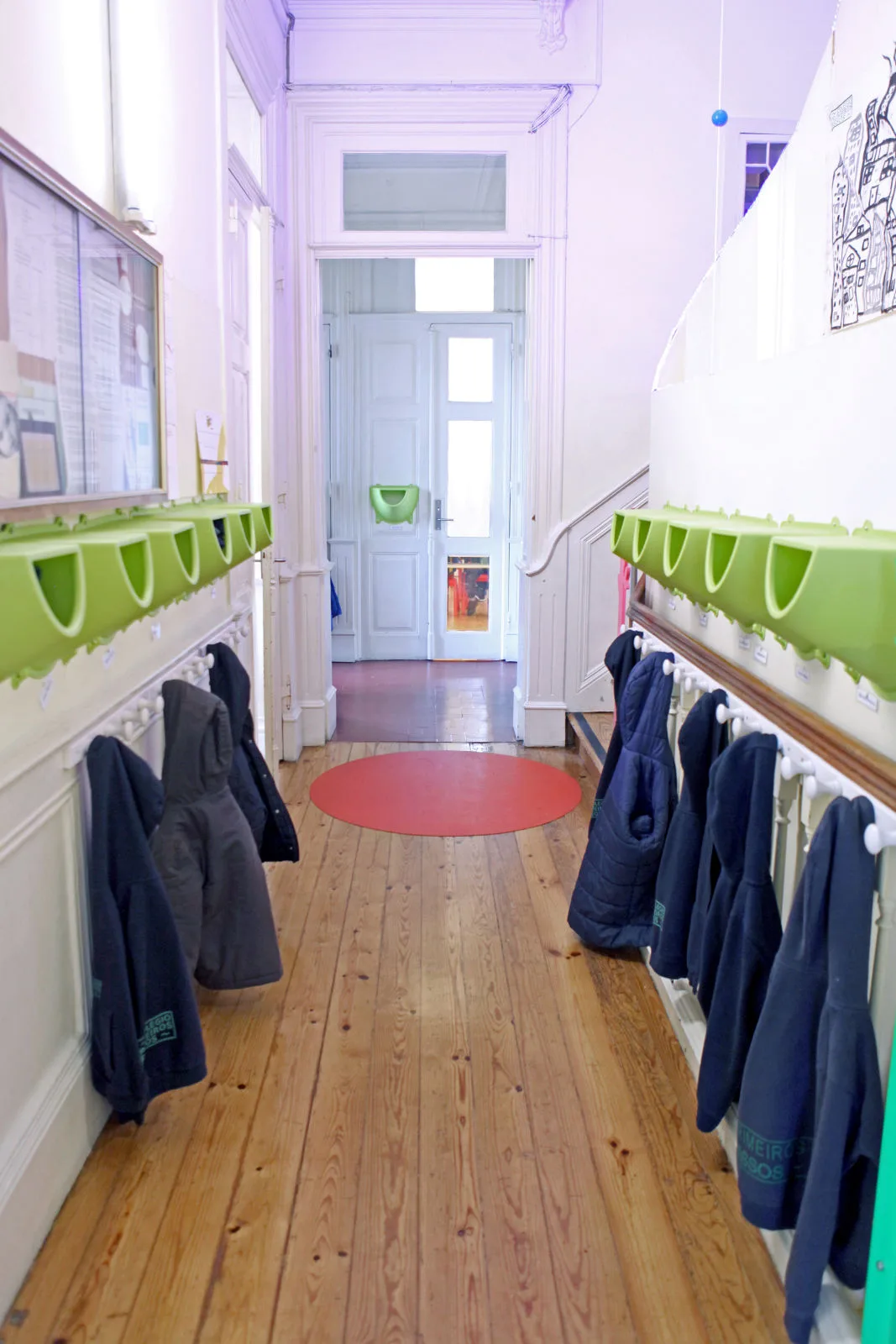 Interior hallway of Colégio Primeiros Passos - Polo de Leça preschool with coat hooks and cubbies.