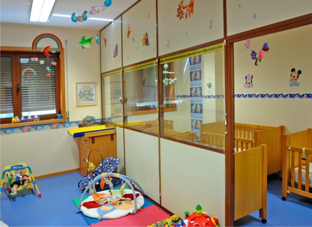 Preschool classroom with cribs, toys, and colorful decorations