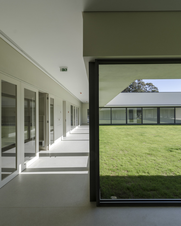 Interior hallway of Cruzada Do Bem preschool with large windows overlooking a grassy courtyard