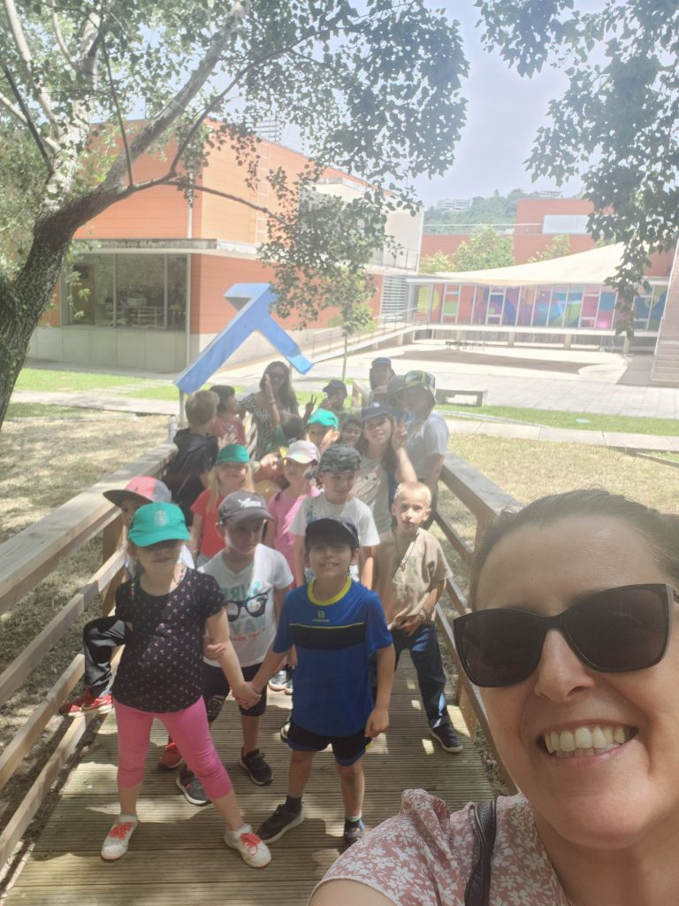 Preschool children on a field trip, walking along a wooden path near the school building.