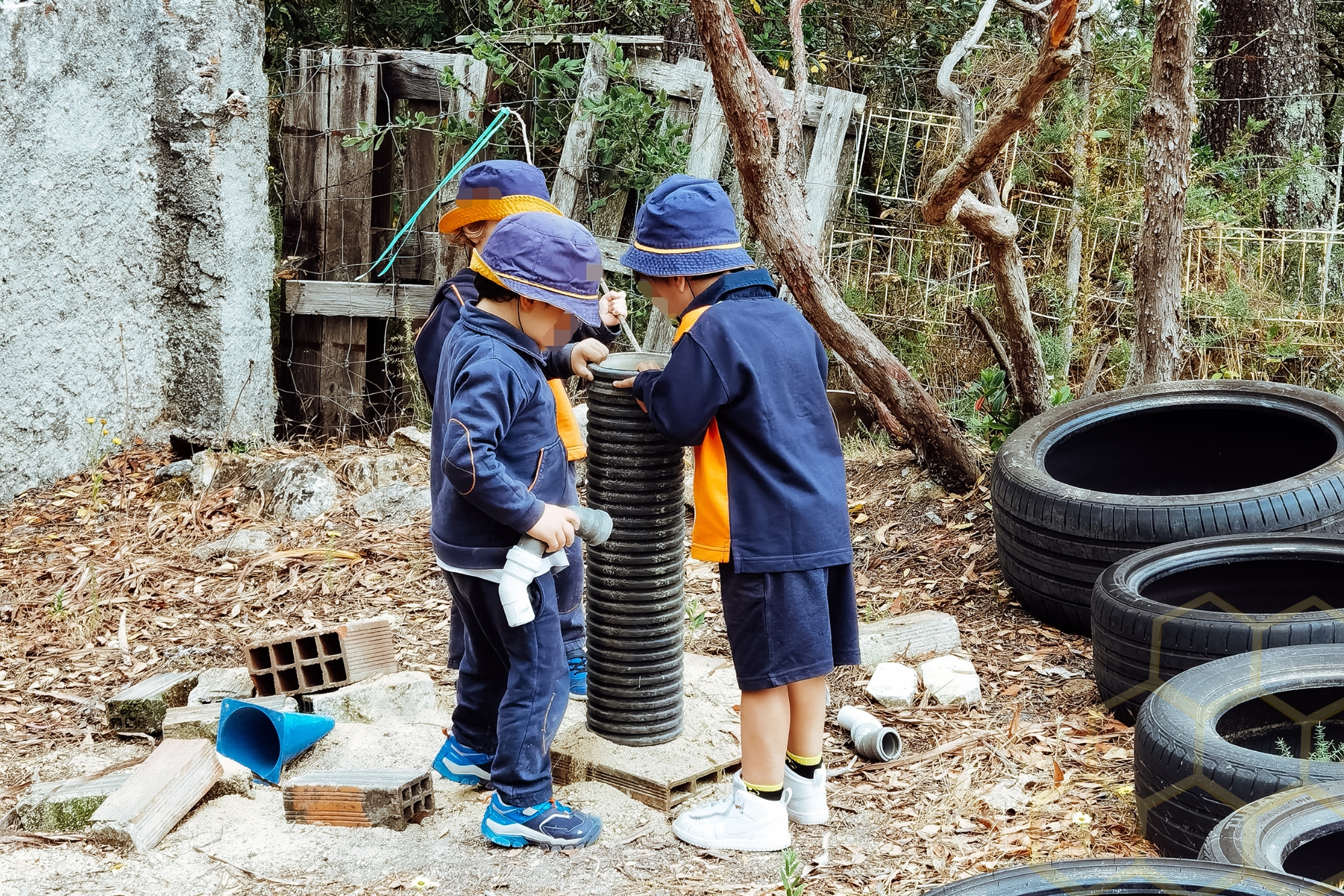 Preschool children playing with pipes and other materials outdoors