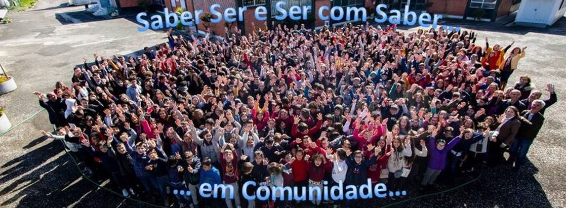 Large group of children, teachers, and staff at Jardim de Infância de Maceirinha preschool in Leiria, Portugal, with their arms raised in celebration.
