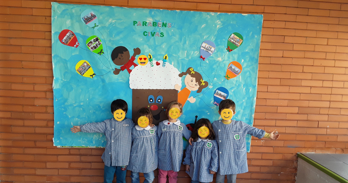 Preschool children at CIVAS smiling for a photo in front of a birthday mural