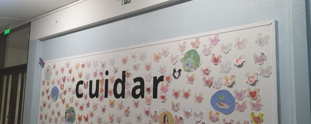 Student artwork adorns a wall inside Colégio Nossa Senhora de Lourdes, depicting hearts and the word 'cuidar' (to care in Portuguese), reflecting the school's values.