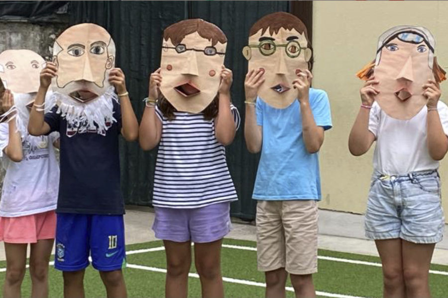 Preschool children playfully holding up self-made masks during an art class.