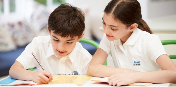 Two students in Prime School International uniforms working together on a school project.