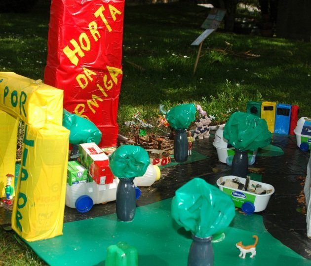 A diorama created by preschool children using recycled materials, depicting a town with trees, buildings, and vehicles.