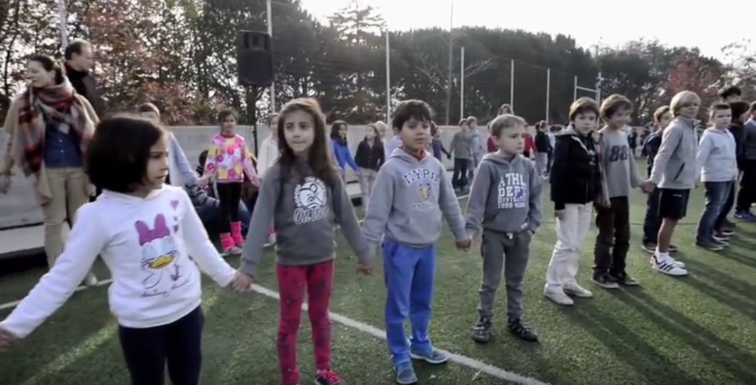 Students holding hands in a circle on a school field