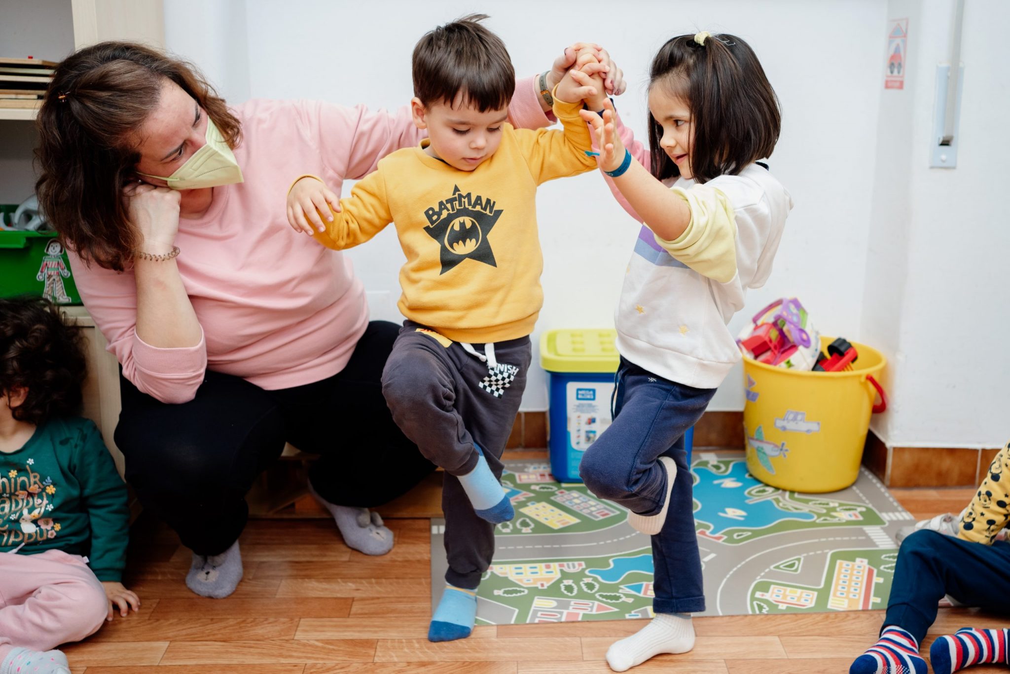 Preschool teacher assisting children with a balance exercise