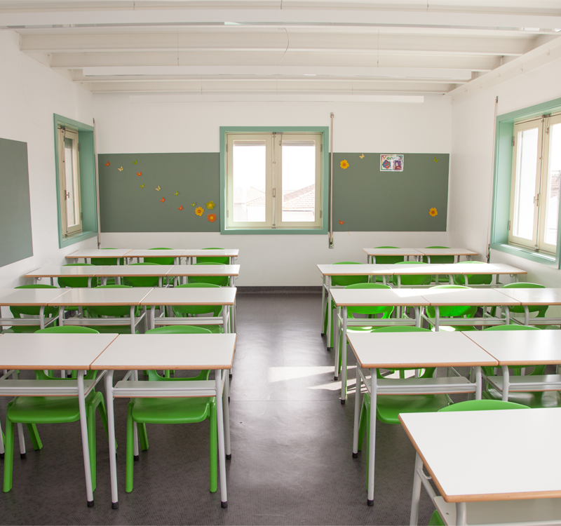 Empty classroom with green chairs and white desks