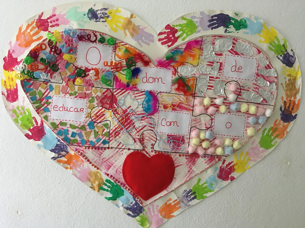 Heart-shaped artwork made of puzzle pieces, decorated with children's handprints and various materials