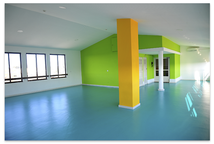 Bright and colorful preschool interior with teal flooring, lime green walls, and a yellow pillar.