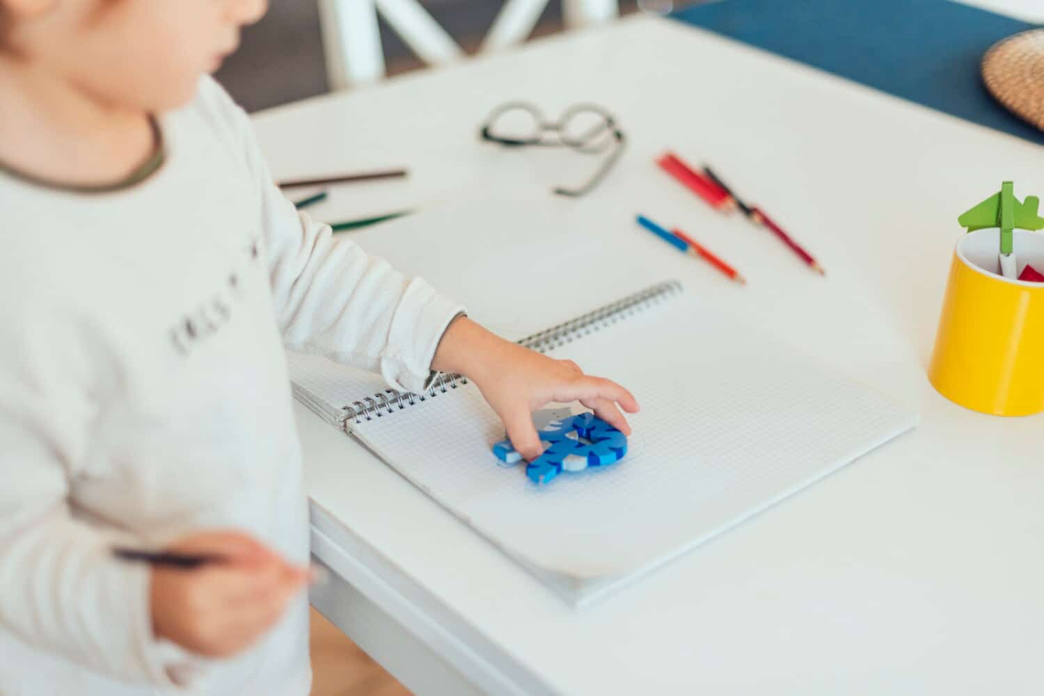 Preschool child playing with a blue puzzle piece at a table