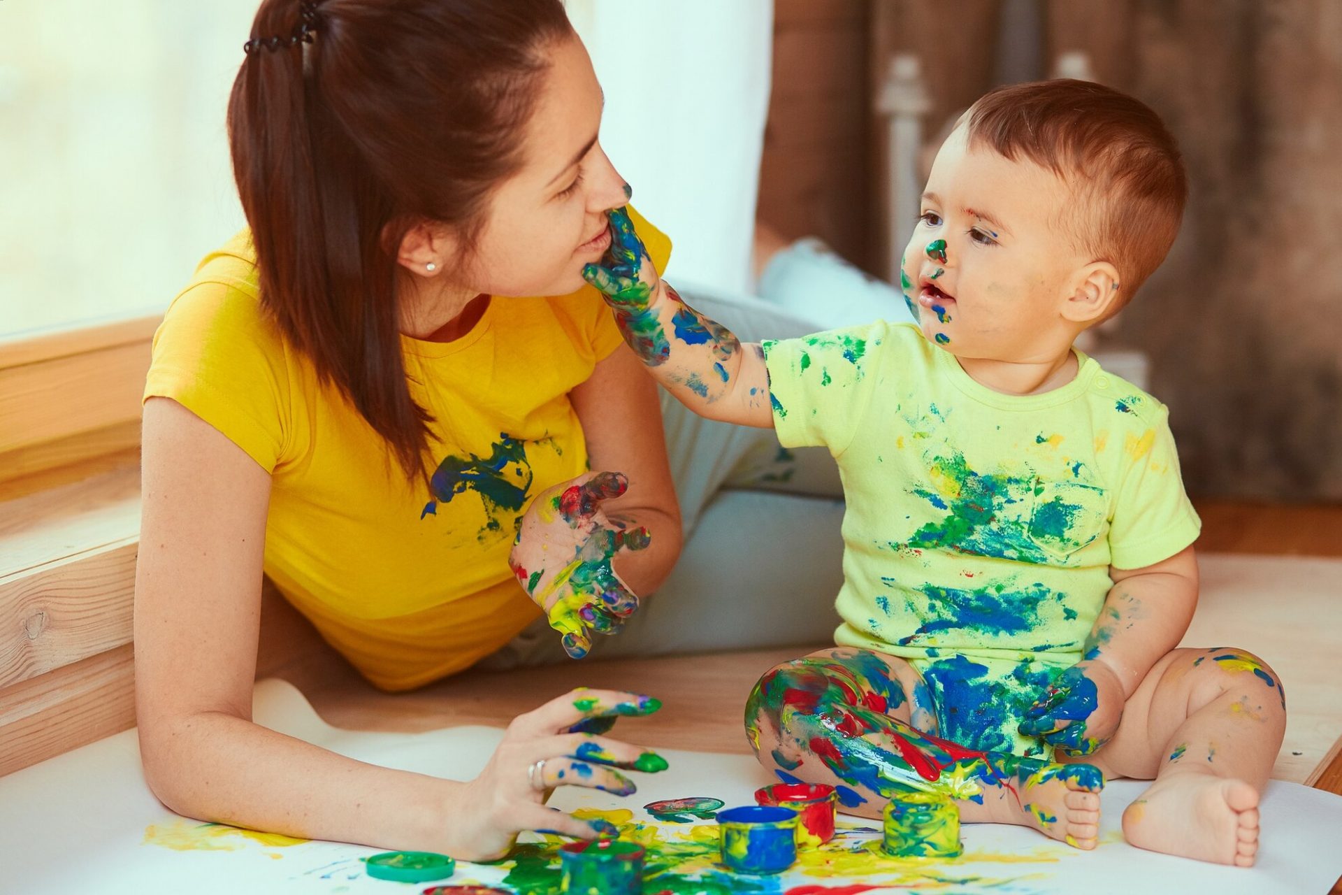 Preschool teacher and child playing with colorful paints