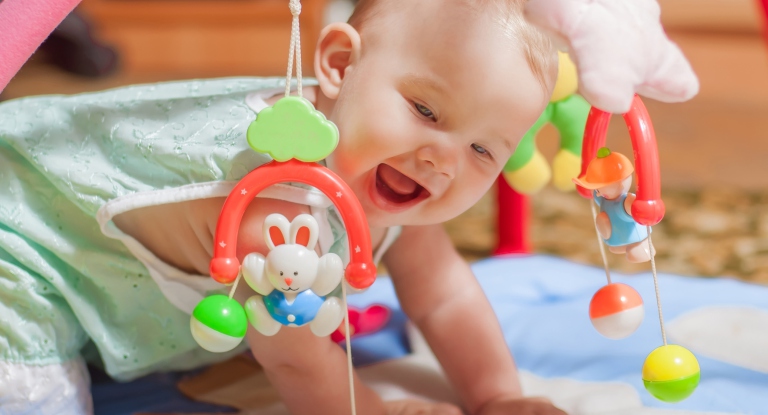Happy baby playing with colorful toys