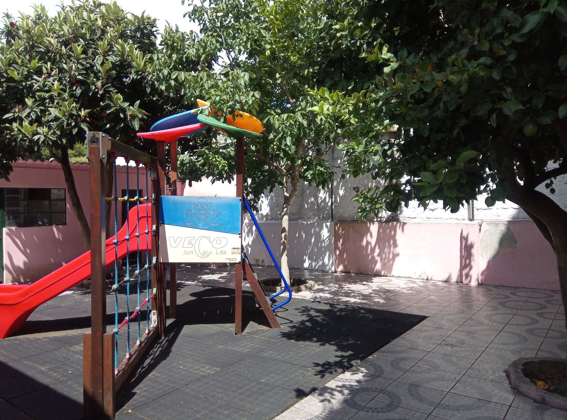 Preschool playground with a red slide and climbing structure