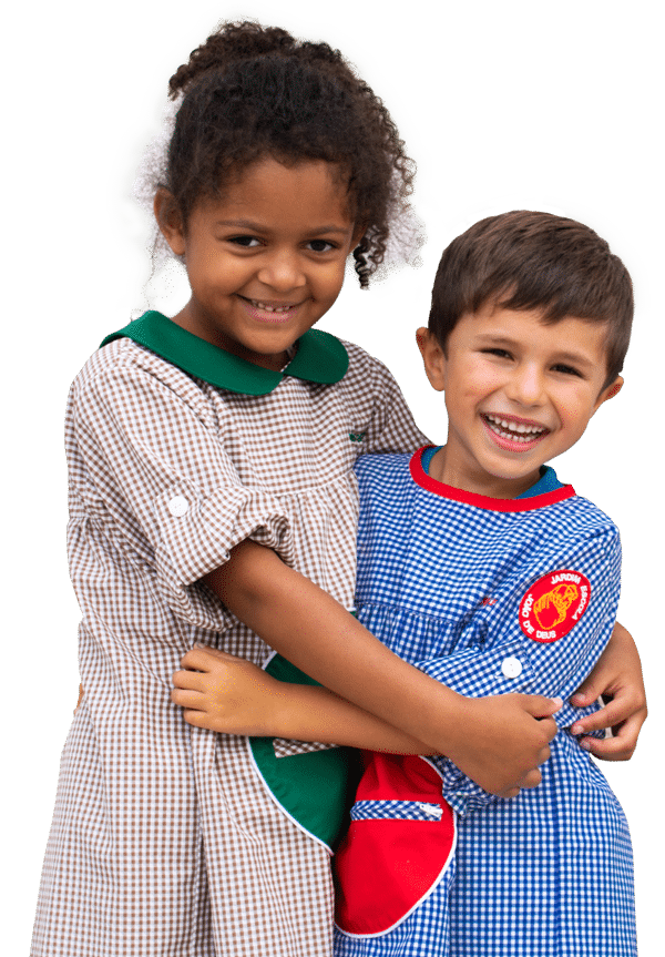 Two happy preschool children hugging each other, wearing school uniforms.