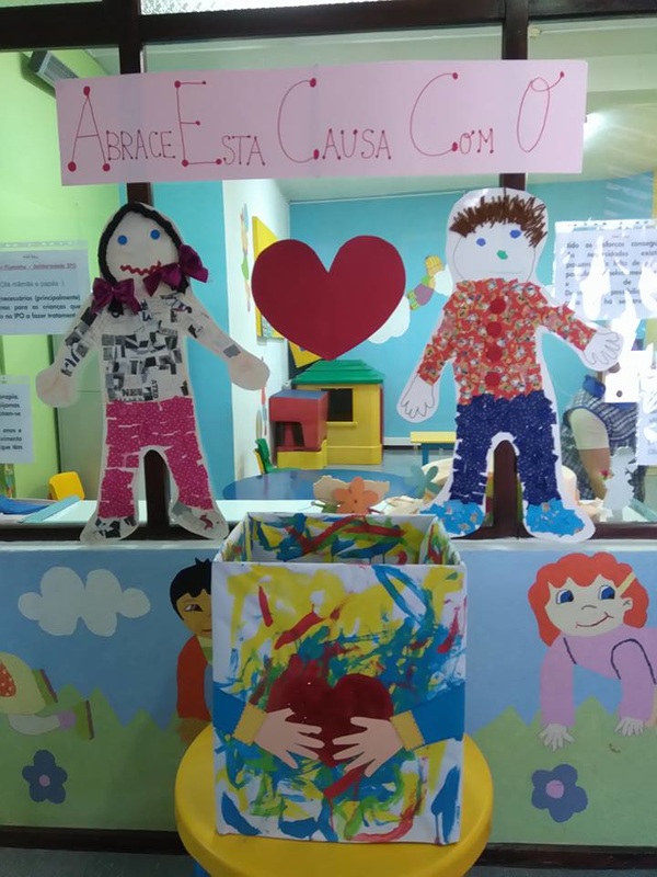 Preschool children's artwork displayed in a classroom, depicting a heart and the phrase "Embrace this cause".