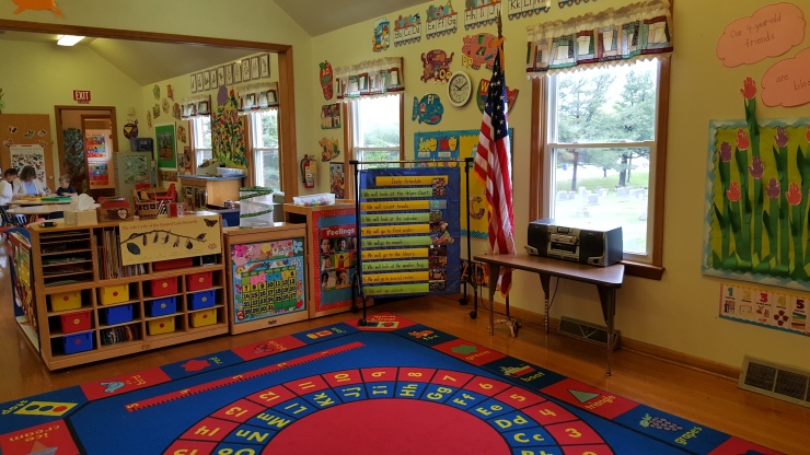 Preschool classroom with colorful decorations, learning materials, and children's artwork.