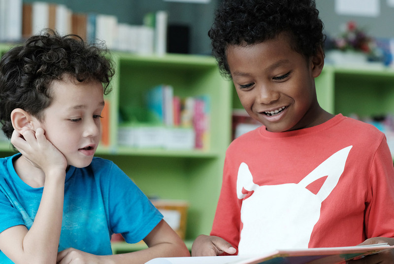 Two preschool children reading a book together in a classroom