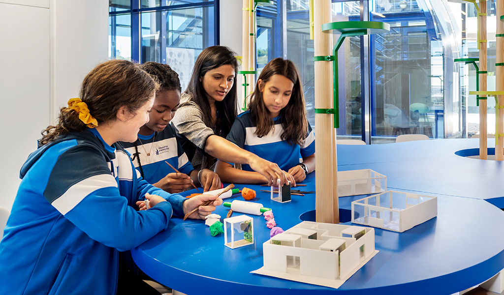 Preschool children engaged in a hands-on architectural design project, collaborating with their teacher.