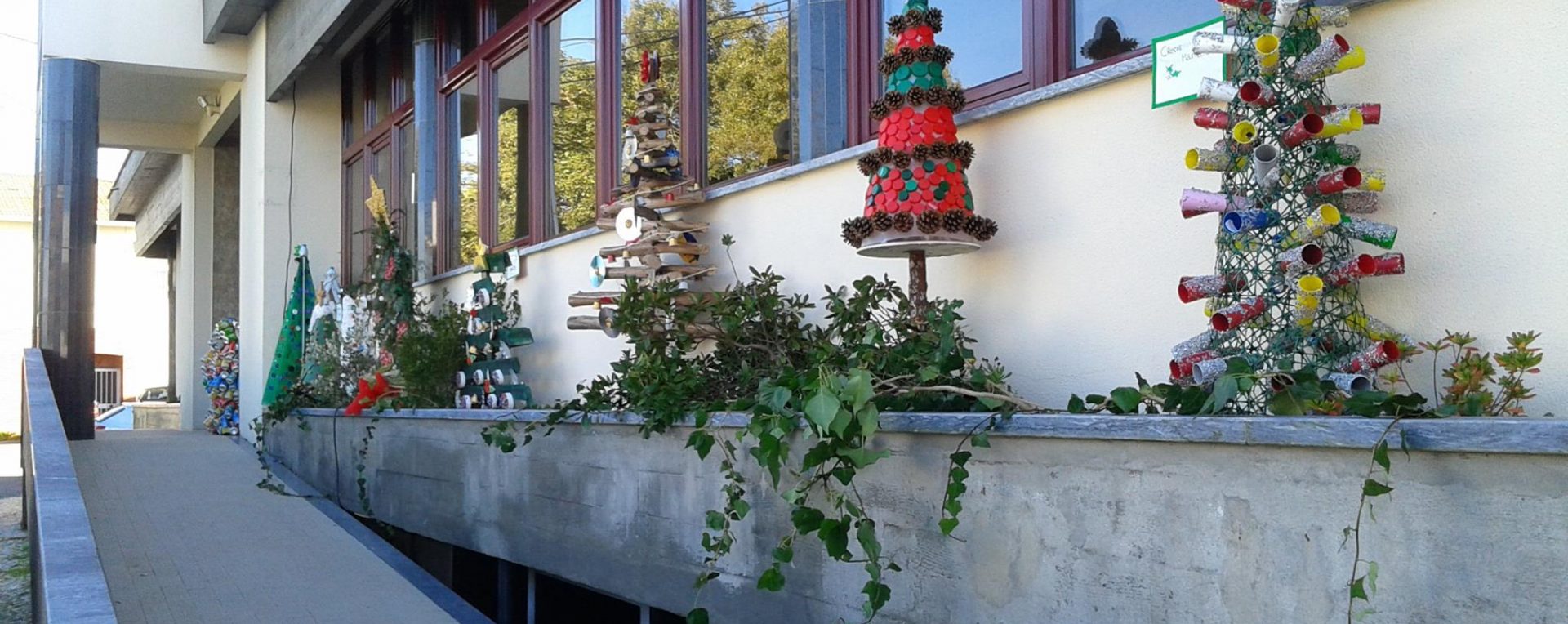 Various handmade Christmas trees made of recycled materials decorate the exterior of Jardim de Infância de Loureira.