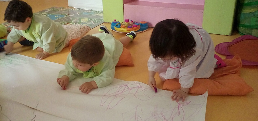 Preschool children drawing on a large sheet of paper