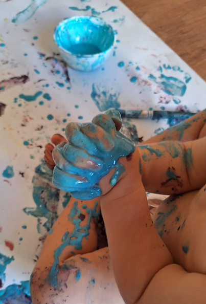 Toddler covered in blue paint during a finger painting activity