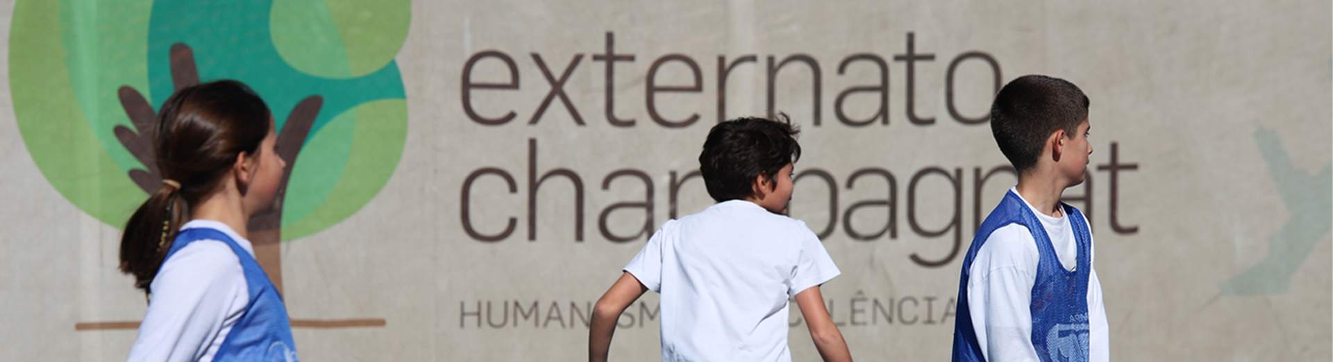 Externato Champagnat students walking near a school wall with the school's logo