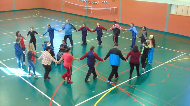 Preschool children and adults holding hands in a circle during a physical activity