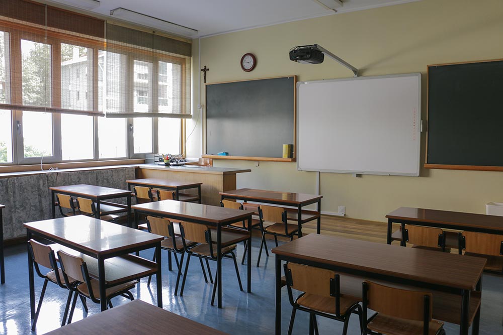 Classroom at Jardim Flori preschool with desks and chairs, whiteboard, and blackboard.