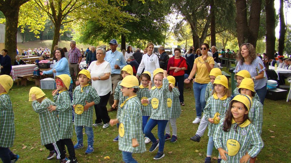 Preschool children in yellow hats participate in an outdoor event.