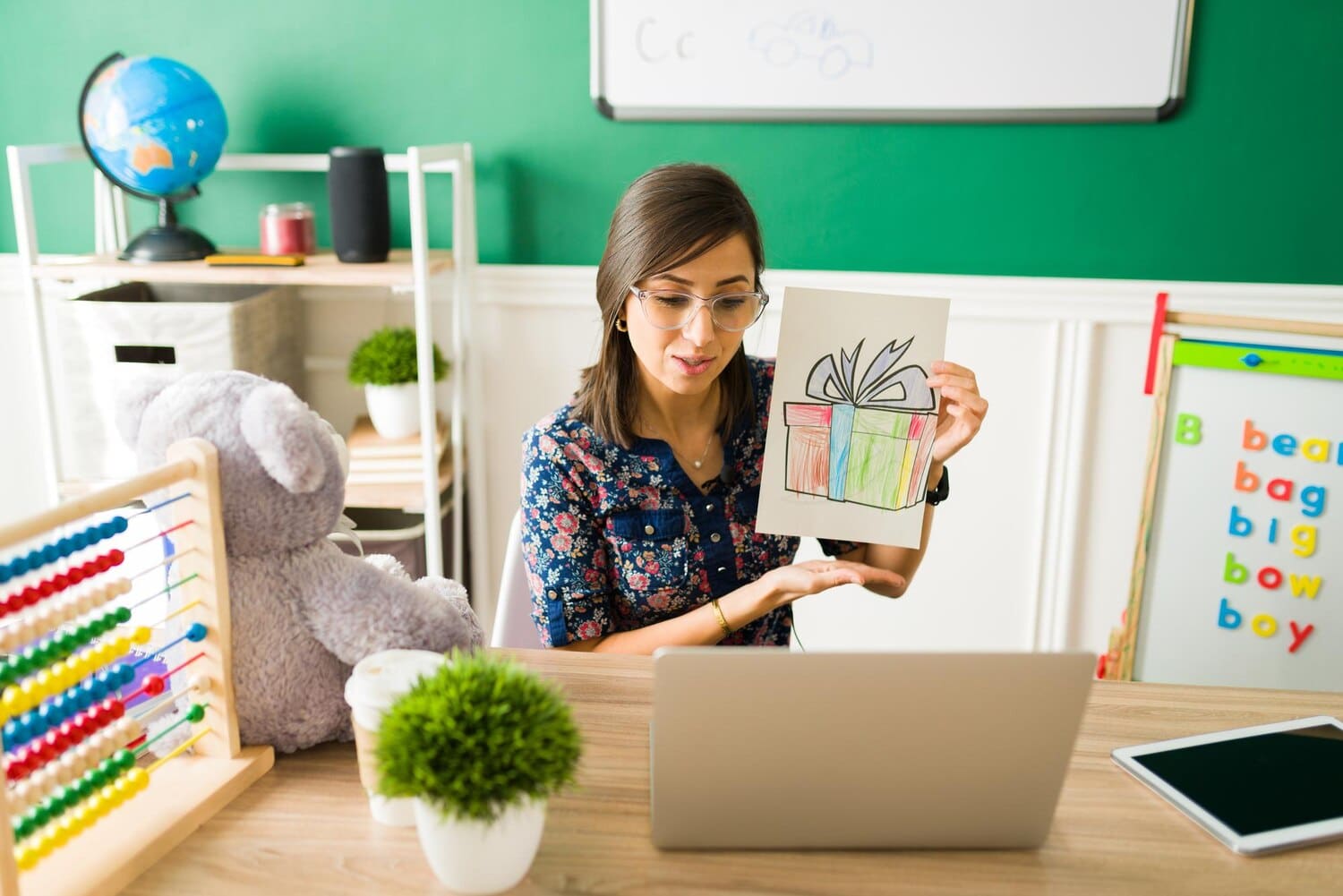 Preschool teacher showing a drawing of a gift during an online class