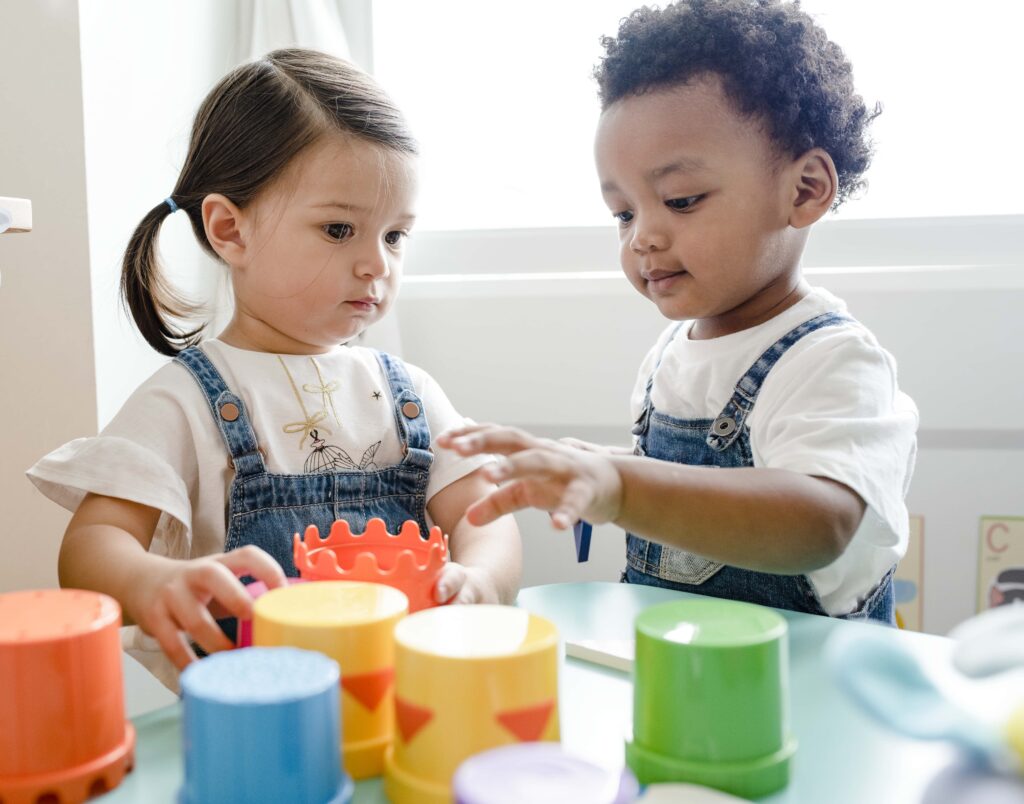 Two preschool children playing with colorful stacking cups