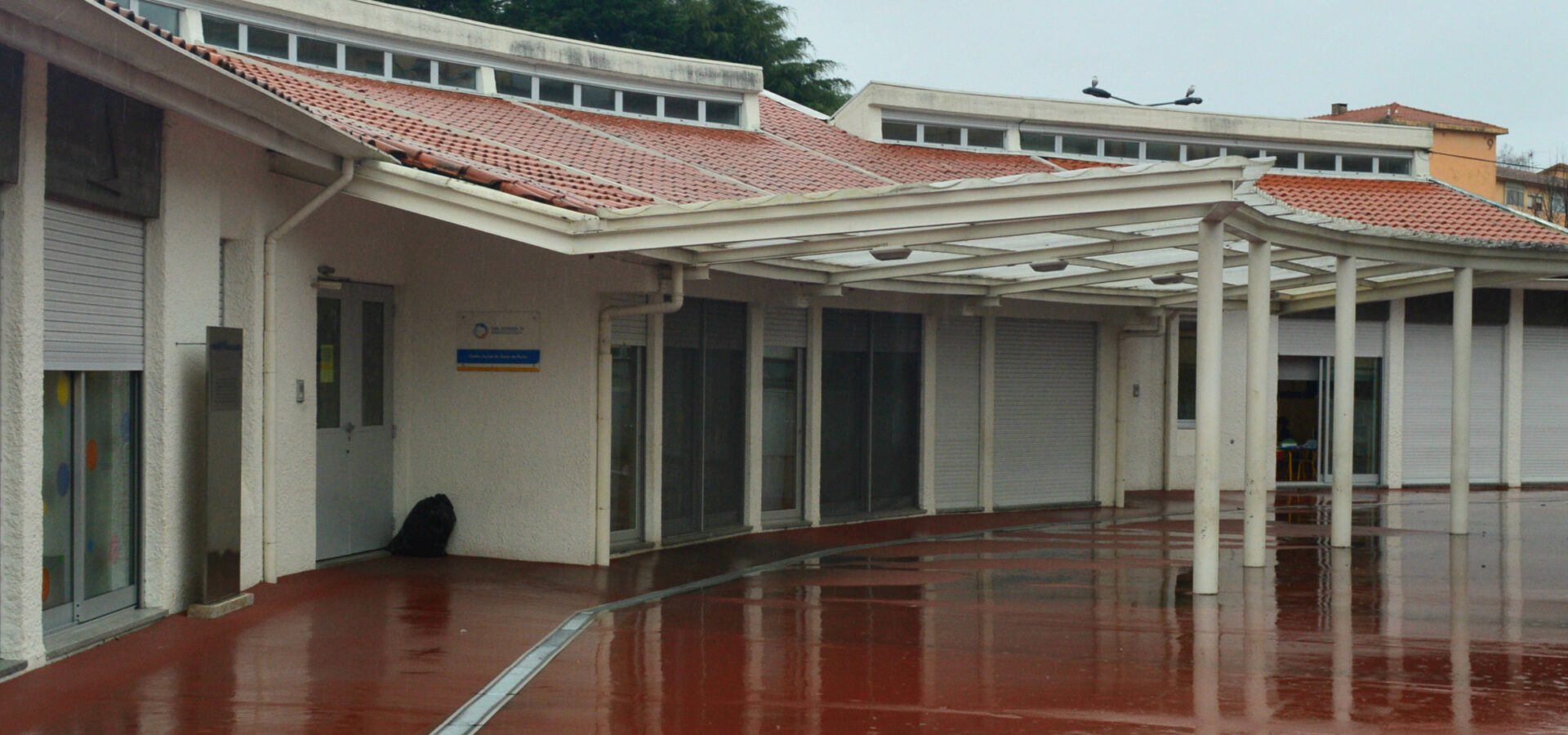 Exterior view of ODPS S. Roque Da Lameira preschool and daycare, showing the building's architecture and red paved courtyard.