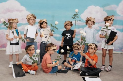 Preschool students in graduation caps and gowns holding roses and certificates