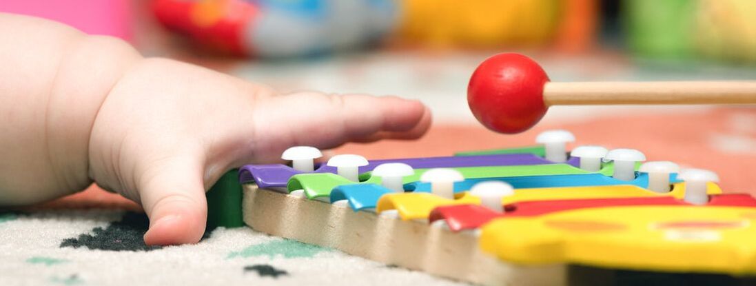 Child's hand playing a colorful xylophone