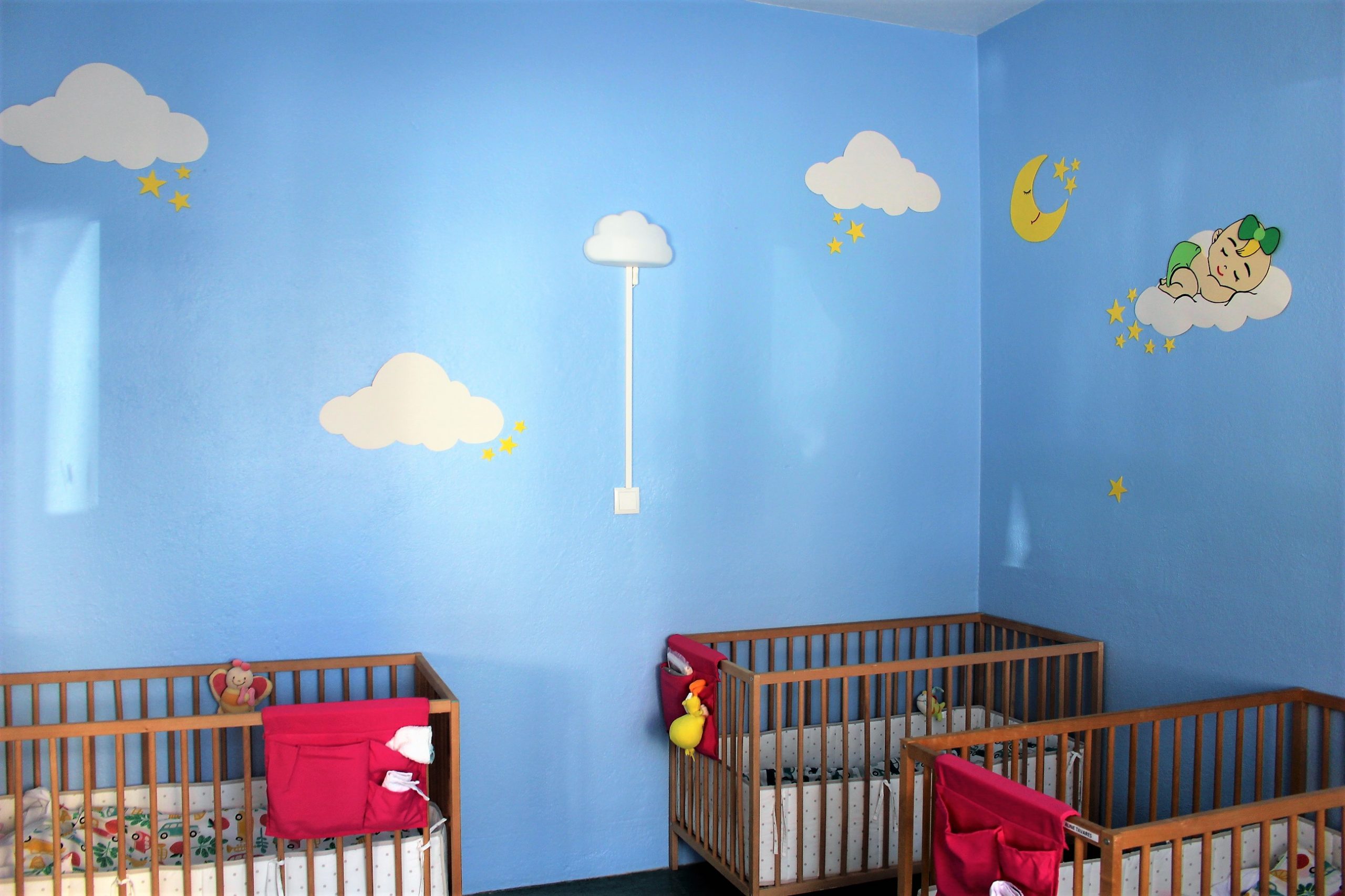 Preschool nursery with cribs and a celestial-themed wall decoration