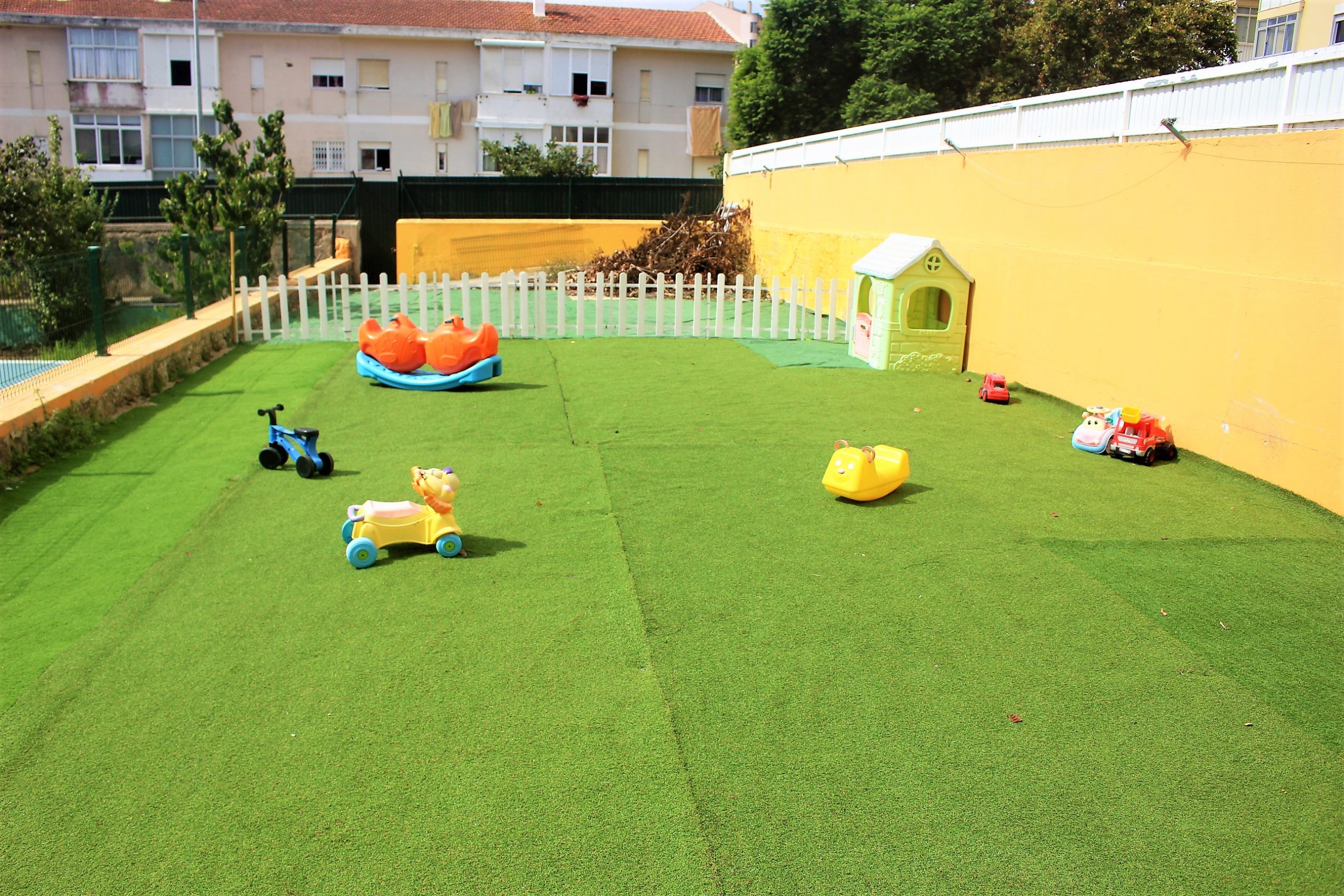 Preschool playground with artificial turf, toys, and a playhouse