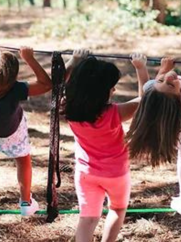 Preschool children playing on a balance beam outdoors