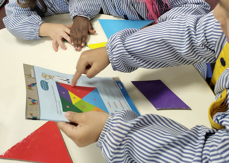 Preschool children participate in a hands-on geometry lesson, manipulating colorful shapes to solve a puzzle.
