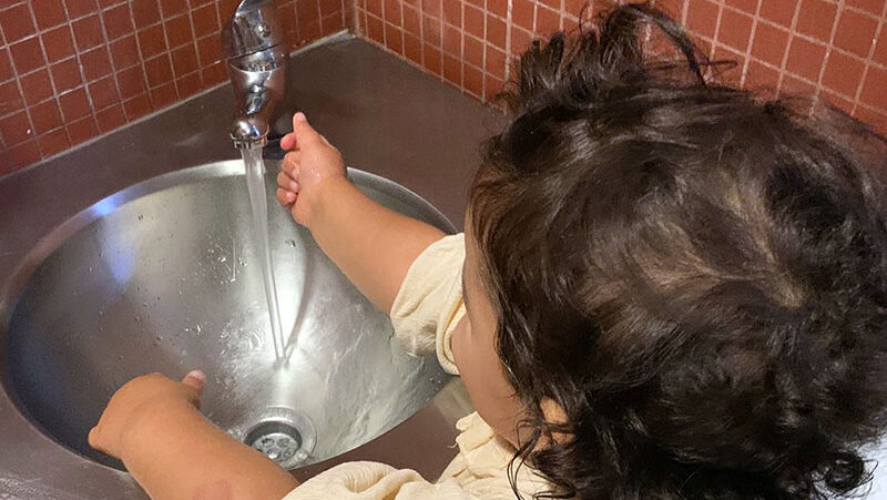 Preschool child washing hands in a sink