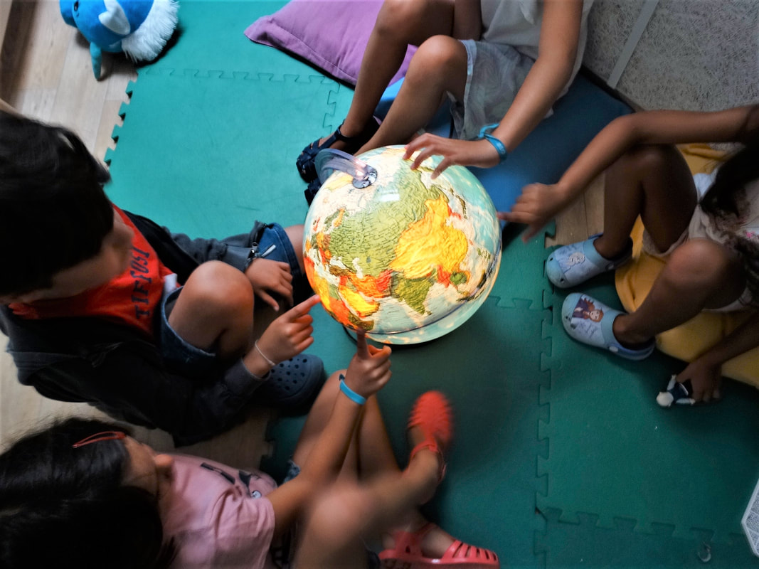 Preschool children gathered around a glowing globe, learning about geography.
