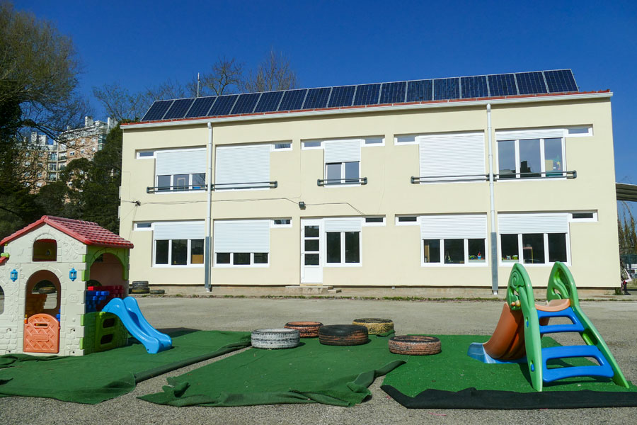 Exterior view of Jardim de Infância da Messa preschool, showing the building and playground equipment.
