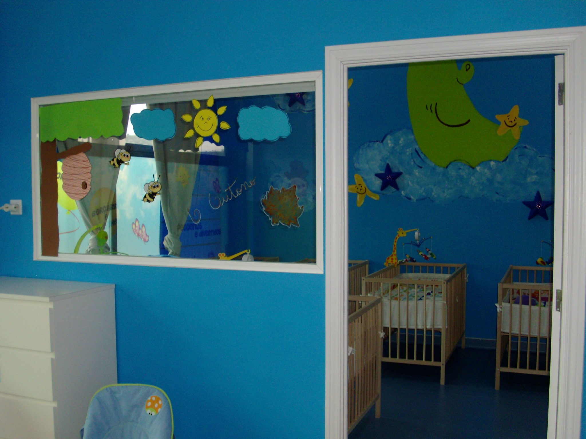 Preschool classroom with blue walls, cribs, and child-friendly decorations